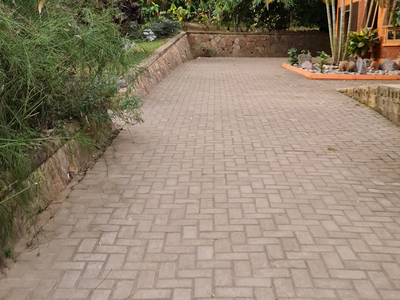 Tan herringbone paver driveway climbing past a stone planting wall
