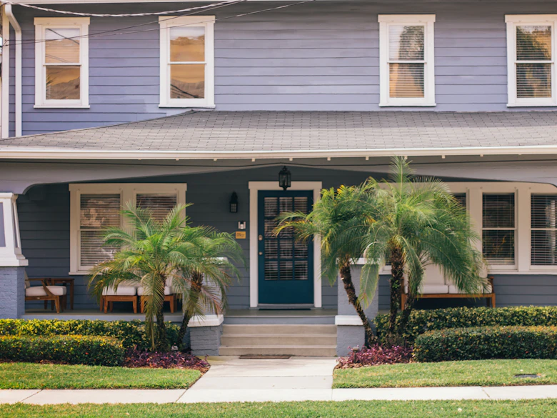 Single-story Florida bungalow with palms at the porch and the original concrete front walk