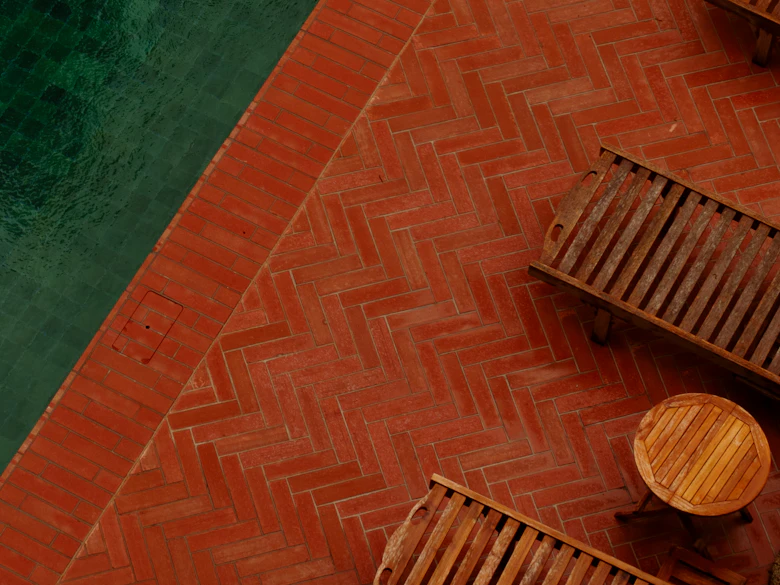 Brick pavers running to the pool edge beneath wooden loungers